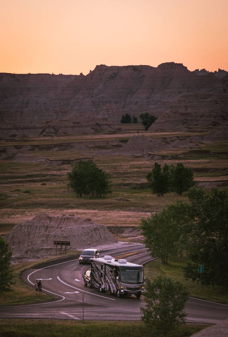 A motorhome on a winding country road at sunset